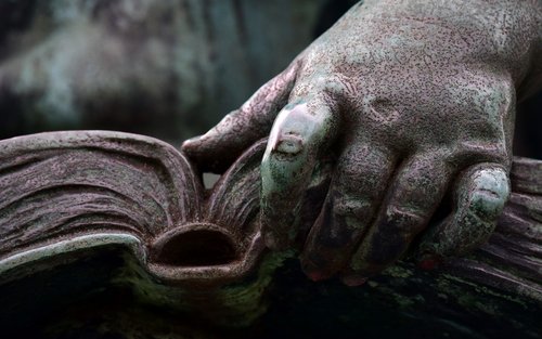 Detailaufnahme einer Statue mit einem offenen Buch in der Hand